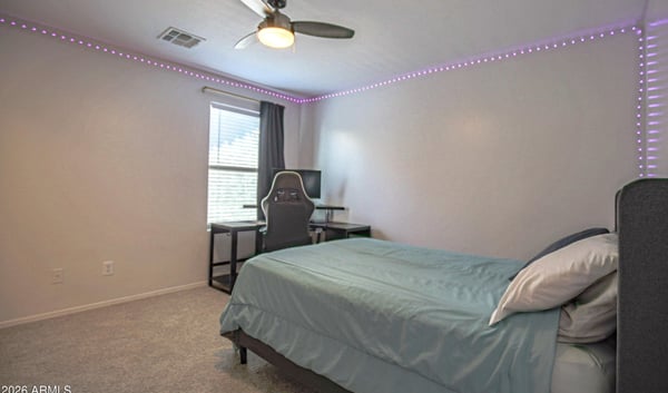 Spacious upstairs bedroom featuring plush carpeting, a ceiling fan, and an open layout with plenty of room for larger furnishings. A comfortable and flexible living space that complements this thoughtfully designed Waddell home.