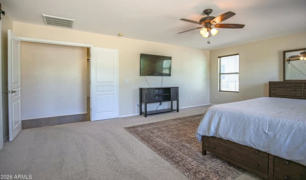 Spacious primary bedroom featuring soft carpeting, a ceiling fan, and an open layout with room for oversized furniture. A comfortable owner's retreat designed for relaxation and everyday living.