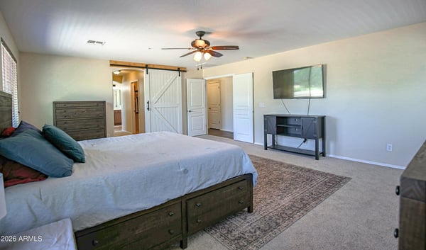 Comfortable primary bedroom with expansive floor space, plush carpeting, entertainment area, and convenient access to the luxurious en-suite bathroom. Designed for everyday comfort in Waddell.
