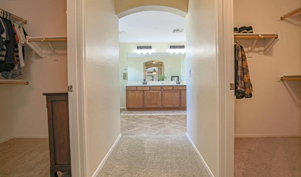 Convenient dressing area connecting dual walk-in closets with the spacious primary bathroom, providing exceptional organization and functionality for the owner's suite in this Waddell home.