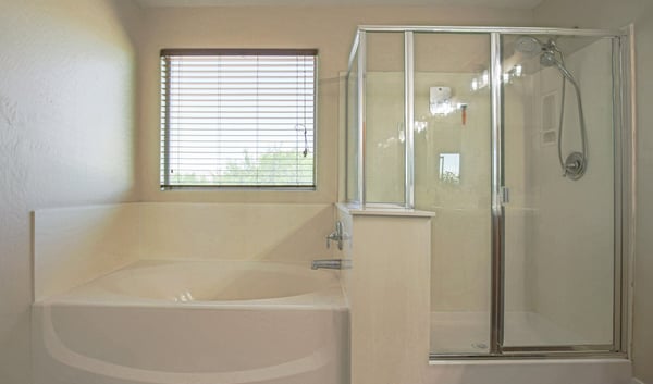Relaxing primary bathroom featuring a deep soaking tub, separate glass shower, natural light, and spacious layout. Designed to provide both comfort and convenience in this Waddell home.