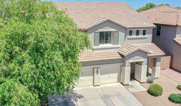 Front aerial image showcasing the home's attractive curb appeal, mature landscaping, three-car garage, and inviting exterior within a desirable Waddell neighborhood.