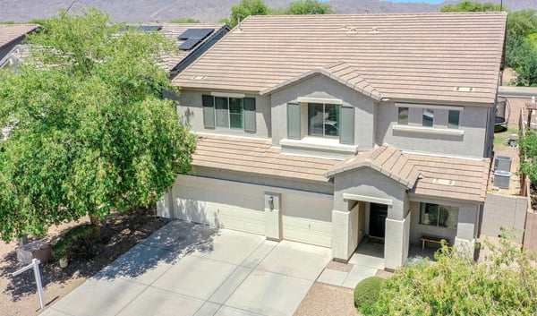 Elevated drone view highlighting the home's impressive exterior, expansive driveway, mature trees, and scenic mountain backdrop. A beautiful overview of this exceptional Waddell proper