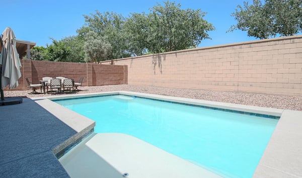 Inviting backyard pool featuring a spacious tanning ledge, modern design, and relaxing patio space. A wonderful outdoor feature that enhances the lifestyle offered by this Waddell property.