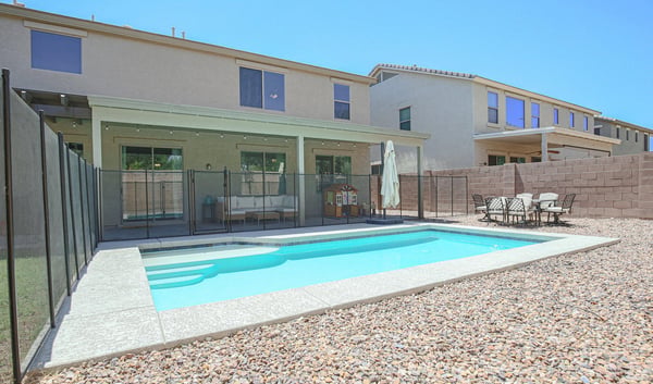 Backyard retreat showcasing a modern swimming pool, safety fence, expansive patio, and easy-care landscaping. Designed for both relaxation and entertaining at this Waddell property.