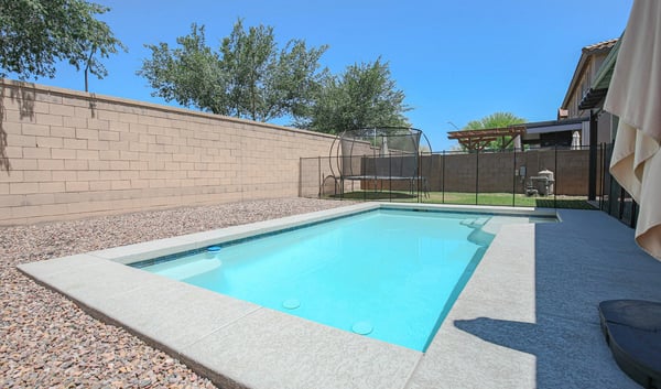 Attractive swimming pool with a baja shelf, surrounding patio, and secure fencing for added peace of mind. A standout feature that complements this beautiful Waddell home.