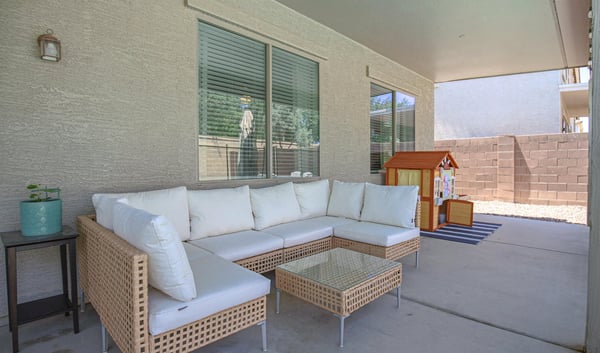 Relaxing covered patio featuring comfortable outdoor seating and views of the backyard entertaining space. A welcoming extension of the home's living area in this desirable Waddell property.