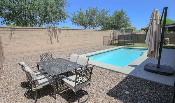 Outdoor dining space positioned beside the sparkling swimming pool, creating the perfect setting for entertaining and enjoying Arizona's outdoor lifestyle. A wonderful backyard feature in this Waddell home.
