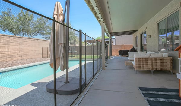 Spacious covered patio with cozy seating, pool views, and direct access to the backyard entertaining area. A relaxing outdoor extension of this beautiful Waddell home's living space.