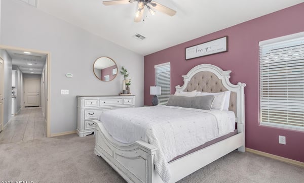 Unwind in the spacious primary suite offering plush carpet, large windows, neutral colors, and generous room for a sitting area or additional furnishings, creating a relaxing retreat.
