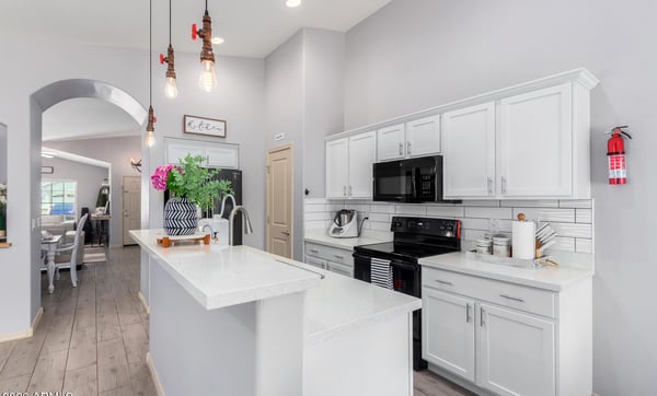 Featuring quartz countertops, subway tile backsplash, white cabinetry, pendant lighting, and generous prep space, this bright kitchen blends timeless style with everyday functionality.