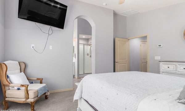 The spacious primary bedroom offers plush carpeting, a ceiling fan, neutral finishes, and convenient access to the ensuite bathroom. A peaceful retreat designed for comfort and relaxation.