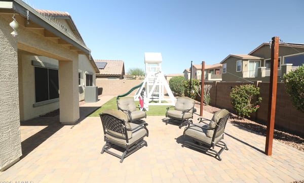 The large paver patio creates the perfect outdoor entertaining space, complemented by artificial turf, mature shrubs, and plenty of seating for relaxing or hosting guests.
