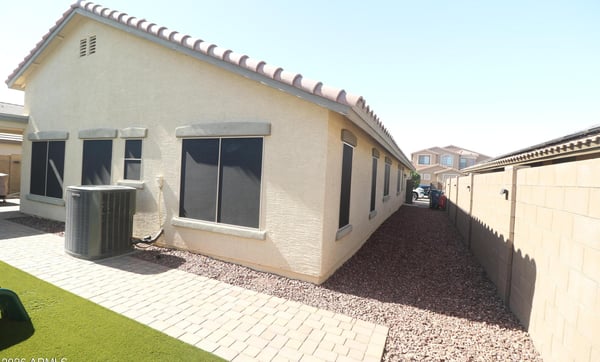 The home's side yard showcases easy-care desert landscaping, paver pathways, and convenient access around the property, providing attractive curb appeal with minimal maintenance in Buckeye.
