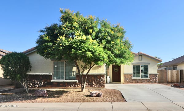 This attractive Buckeye home welcomes you with mature shade trees, stone-accented architecture, desert landscaping, and a spacious driveway leading to the attached two-car garage. Exceptional curb appeal makes a lasting first impression.