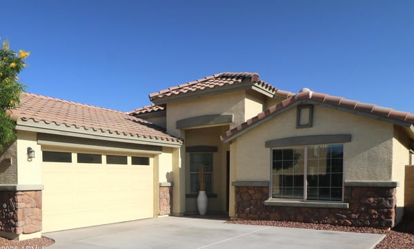 The charming covered entry and stone-accented exterior create a warm welcome while the spacious driveway and attached garage add everyday convenience to this beautifully maintained Buckeye property.