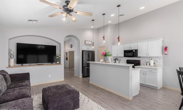 The stylish kitchen showcases white quartz countertops, white cabinetry, recessed lighting, a spacious breakfast bar, and open sightlines to the family room, making meal preparation and entertaining easy.