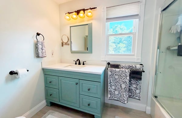Full Bath w/ New LVP flooring 2026, newer vanity/sink & cabinets refreshed in 2026, cordless shade, OH vent/light, fiberglass tub/shower w/ updated glass sliding doors