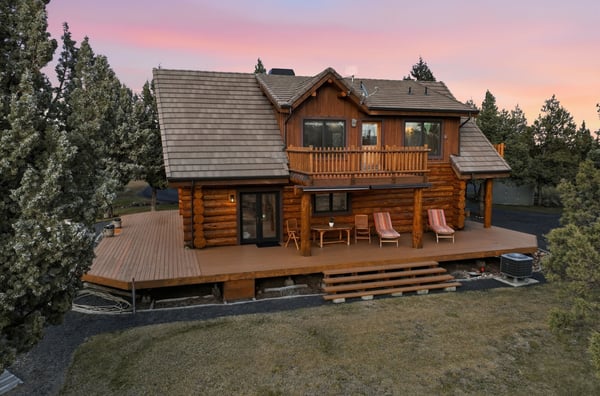 This inviting log home features a spacious deck and picturesque surroundings, perfect for outdoor relaxation.