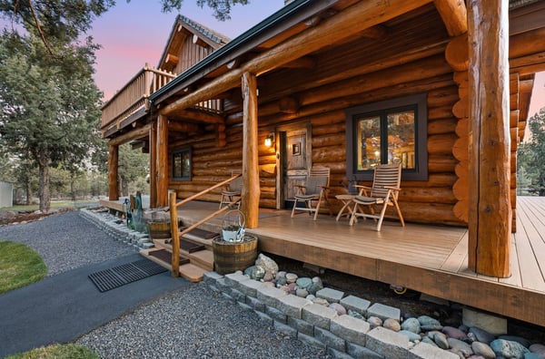 Experience rustic living in this log cabin home featuring a spacious porch and natural landscaping.