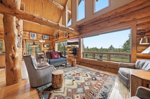 Experience rustic warmth in this open-concept log cabin, featuring expansive windows with stunning outdoor views.