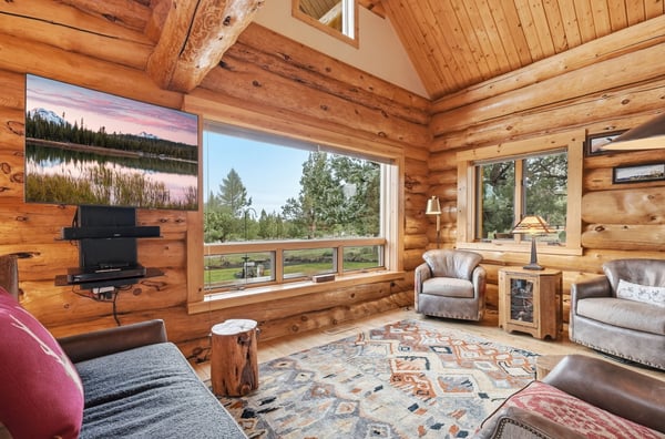 Cozy log cabin with expansive windows, inviting natural light and stunning views of the surrounding landscape.