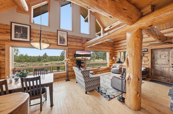 Spacious log cabin living area featuring large windows that showcase scenic views and abundant natural light.