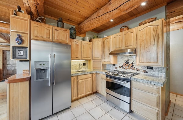 This spacious kitchen features natural wooden cabinetry, modern appliances, and striking stone accents throughout.