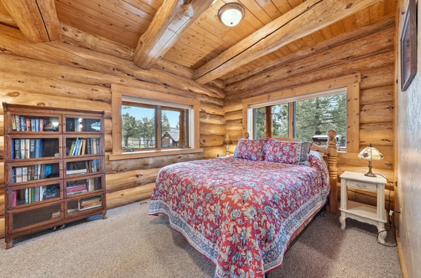 Cozy log cabin bedroom featuring natural wood beams, ample light, and scenic views for restful retreats.