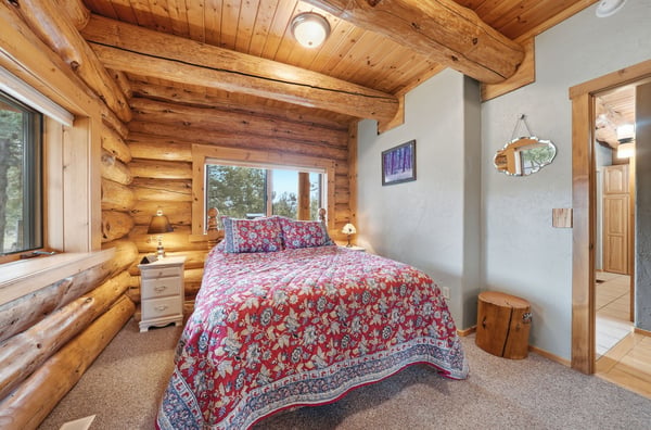 Cozy log cabin bedroom featuring natural wood accents and large windows that invite abundant light.