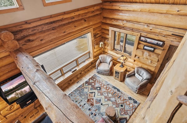 Cozy log cabin with inviting seating area and natural light, perfect for relaxation and gatherings.
