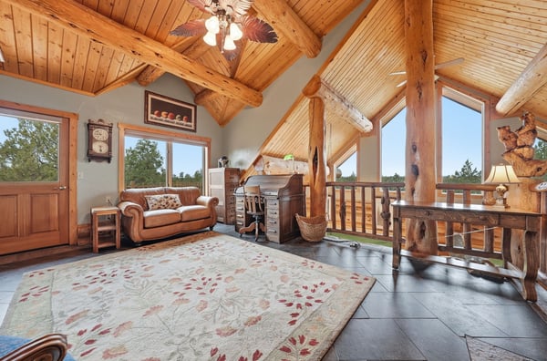 Spacious loft-style living area features dramatic wood beams and large windows, inviting natural light, and stunning views.