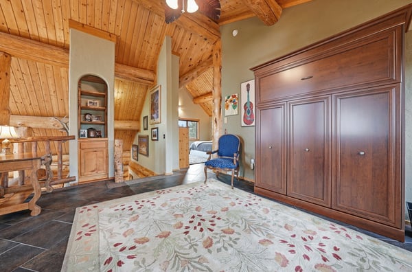 The spacious loft, open to the great room below, features a Murphy Bed for guests, a cozy seating area, and one of three private balconies.