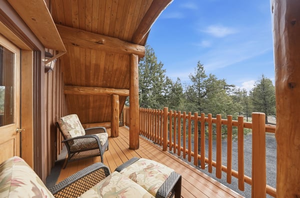 Enjoy expansive outdoor views from this inviting balcony equipped with comfortable seating and natural wood details.
