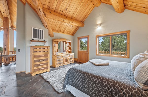 Spacious bedroom featuring natural wood accents, large windows, and two private balconies with scenic views.