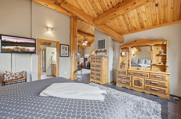 Spacious bedroom featuring vaulted ceilings, natural wood accents, and modern amenities for ultimate comfort.
