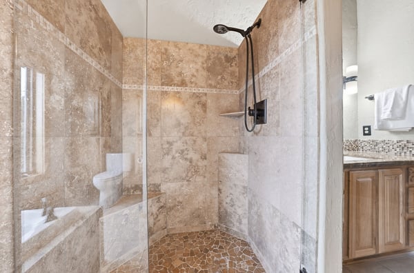 Discover a spacious walk-in shower featuring natural stone and modern fixtures for an inviting experience.