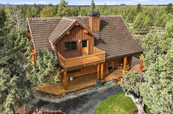 Stunning log cabin surrounded by lush greenery, featuring expansive outdoor spaces and picturesque views.