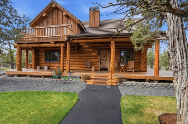 Rustic log cabin with spacious porch, surrounded by nature and conveniently located near outdoor adventures.