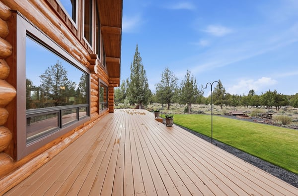 Spacious log home deck with ample outdoor space, surrounded by scenic landscapes and lush greenery.