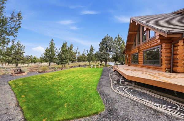 This log cabin offers spacious outdoor living with expansive green lawns and beautiful surrounding landscapes.