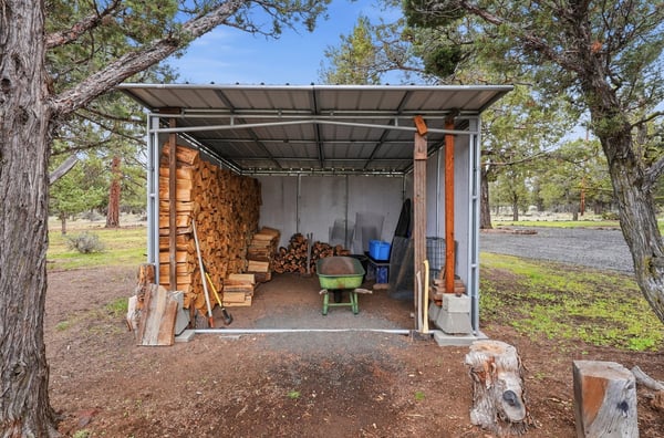 Spacious wood storage shed equipped with ample space for tools and firewood, set amid nature.