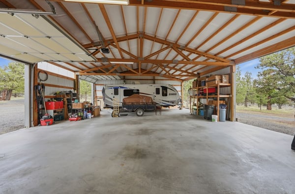 Spacious, well-lit garage perfect for RV storage and versatile workspace, surrounded by natural scenery.