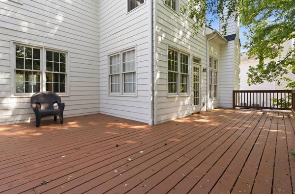 Spacious wood deck perfect for gatherings, surrounded by natural light and nearby greenery.