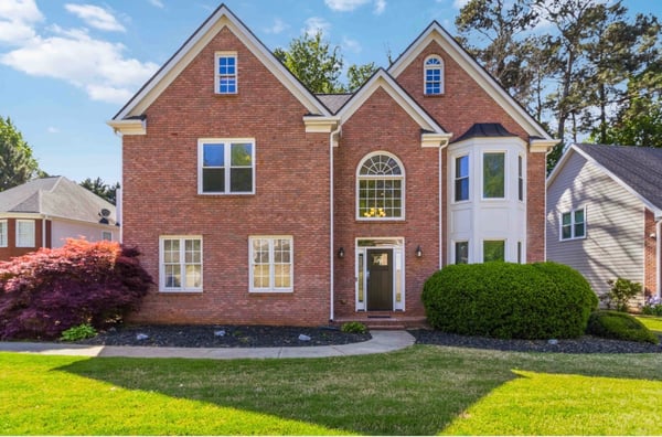 This attractive brick home features a spacious layout, large windows, and a well-maintained front yard.