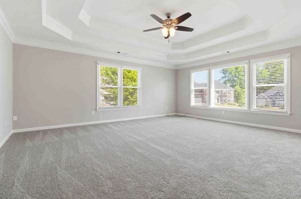 Spacious, light-filled primary bedroom featuring a coffered ceiling and large windows for ample natural light.