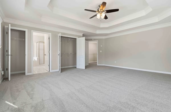 Spacious primary bedroom featuring a coffered ceiling, dual closets, and a bright en-suite bathroom.
