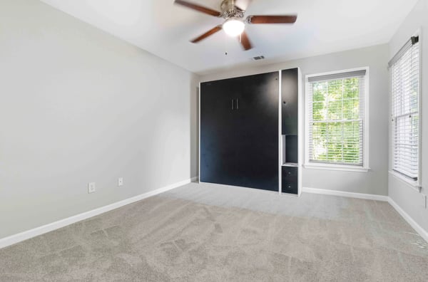 Bright and versatile room featuring a wall-mounted murphy bed, perfect for maximizing space and comfort.