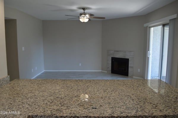 Comfortable living room featuring a modern tiled fireplace, updated flooring, ceiling fan, and sliding glass doors opening to the patio. This inviting space is ideal for everyday living and entertaining.