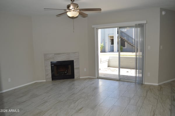 Spacious living area with updated tile flooring, cozy fireplace, ceiling fan, and abundant natural light from the sliding glass doors. The open layout enhances the home's comfortable and move-in-ready appeal.